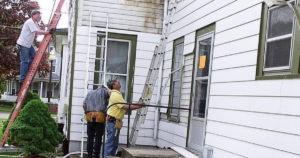 Workers repairing a damaged house exterior.