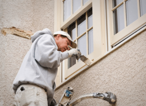 A man painting the house in summer. 
